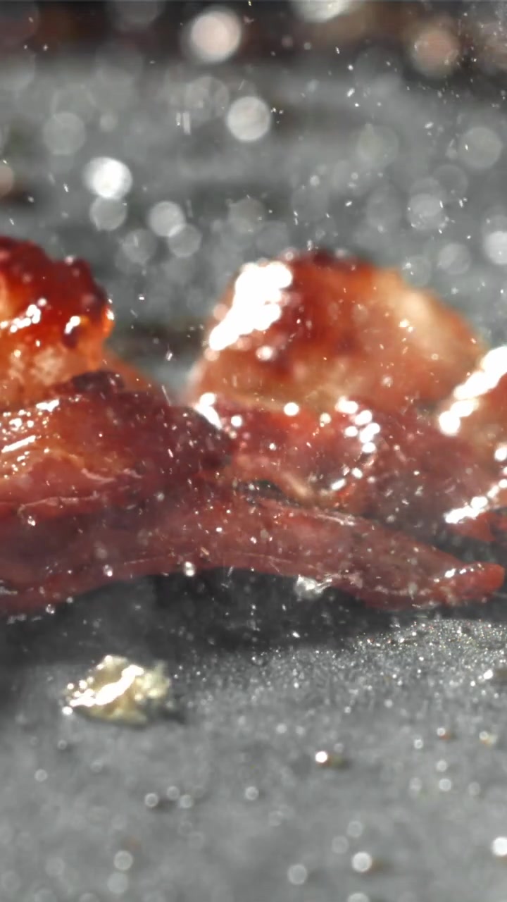 Primo piano di pancetta che sfrigola e frigge in una padella calda.
