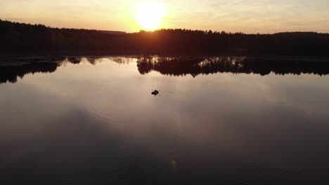 Bote-De-Goma-En-Medio-De-Un-Lago-Tranquilo-Durante-La-Hora-Dorada-Cerca-Del-Pueblo-De-Rogowko,-Polonia