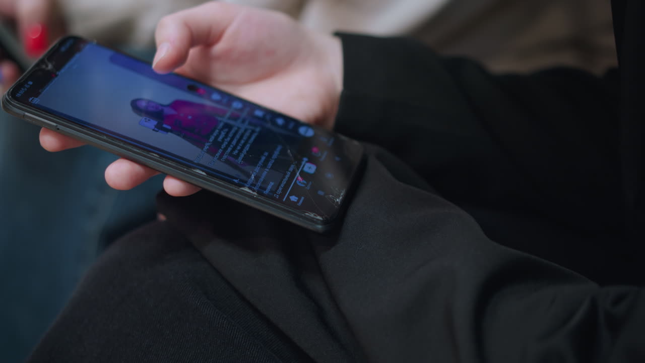 Close up of hand holding smartphone showing person watching social media video with focus on screen displaying online content, digital lifestyle and entertainment