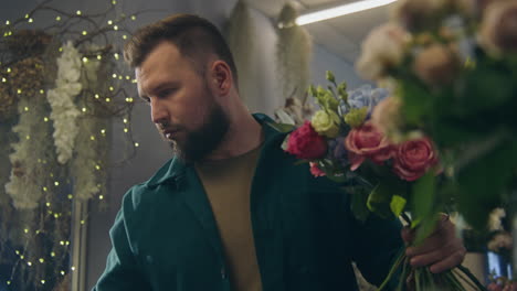 florist adds branches to bunch and looks on it