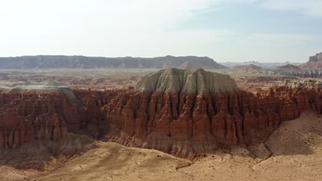 gorgeous trucking right aerial drone shot of the beautiful goblin valley utah state park with pointy red hoodoo rock formations and red and white butte's looming above on a warm sunny summer day