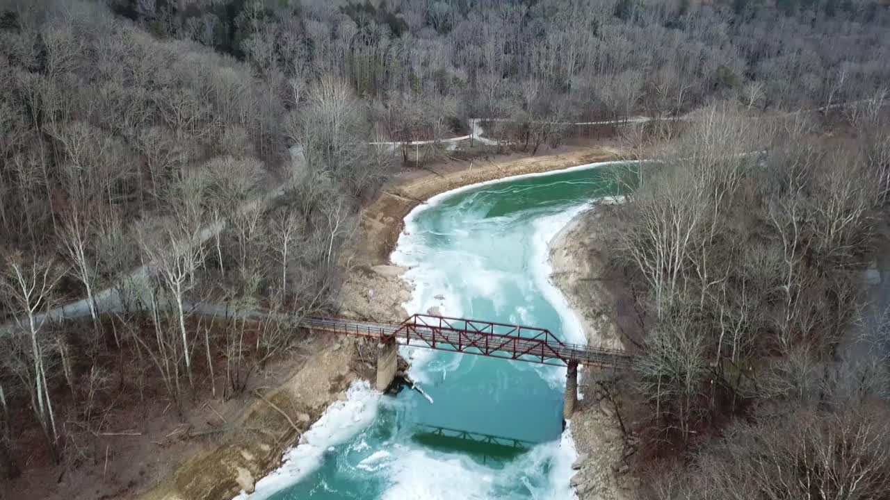 acantilados invernales, montañas, río helado y puente peatonal