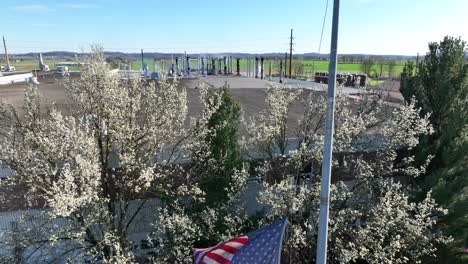 american flag waving in front of industrial building in spring