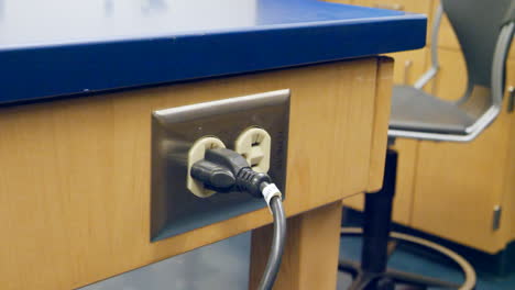 primer plano de un científico conectando una pieza de tecnología de investigación médica en un enchufe eléctrico durante un experimento en un laboratorio