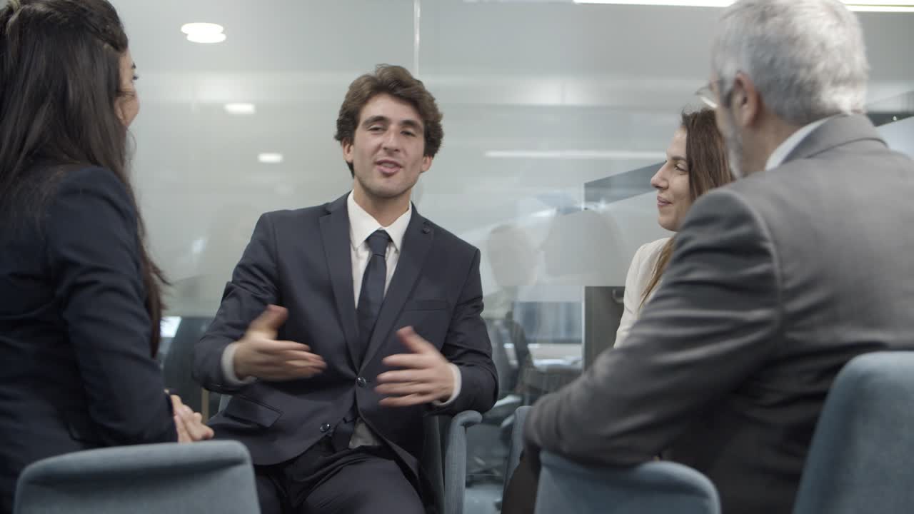 compañeros de trabajo alegres sentados en sillas y estrechándose las manos