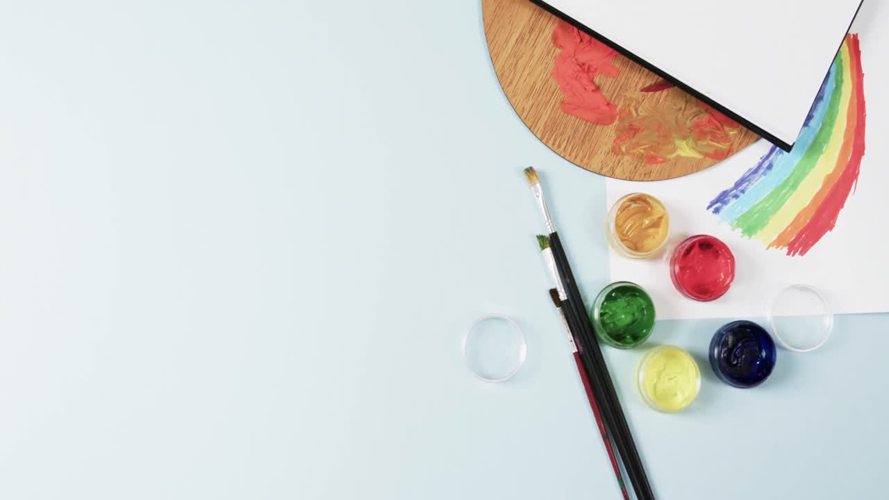 녹화 공간과 함께 파란색 배경에 노트북, 질 및 페인트의 오버헤드 뷰, 느린 동작