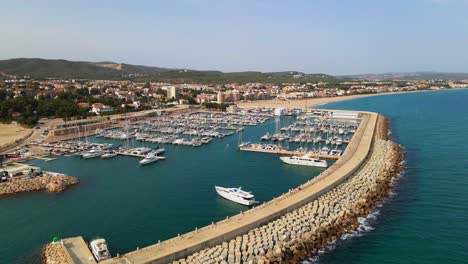 Aerial-4K-drone-footage-of-marina-next-to-El-Roc-de-Sant-Gaietà,-a-scenic-location