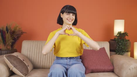 woman making heart sign at camera.