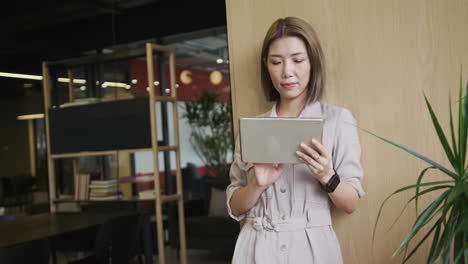 asian businesswoman standing using a digital tablet in a modern office