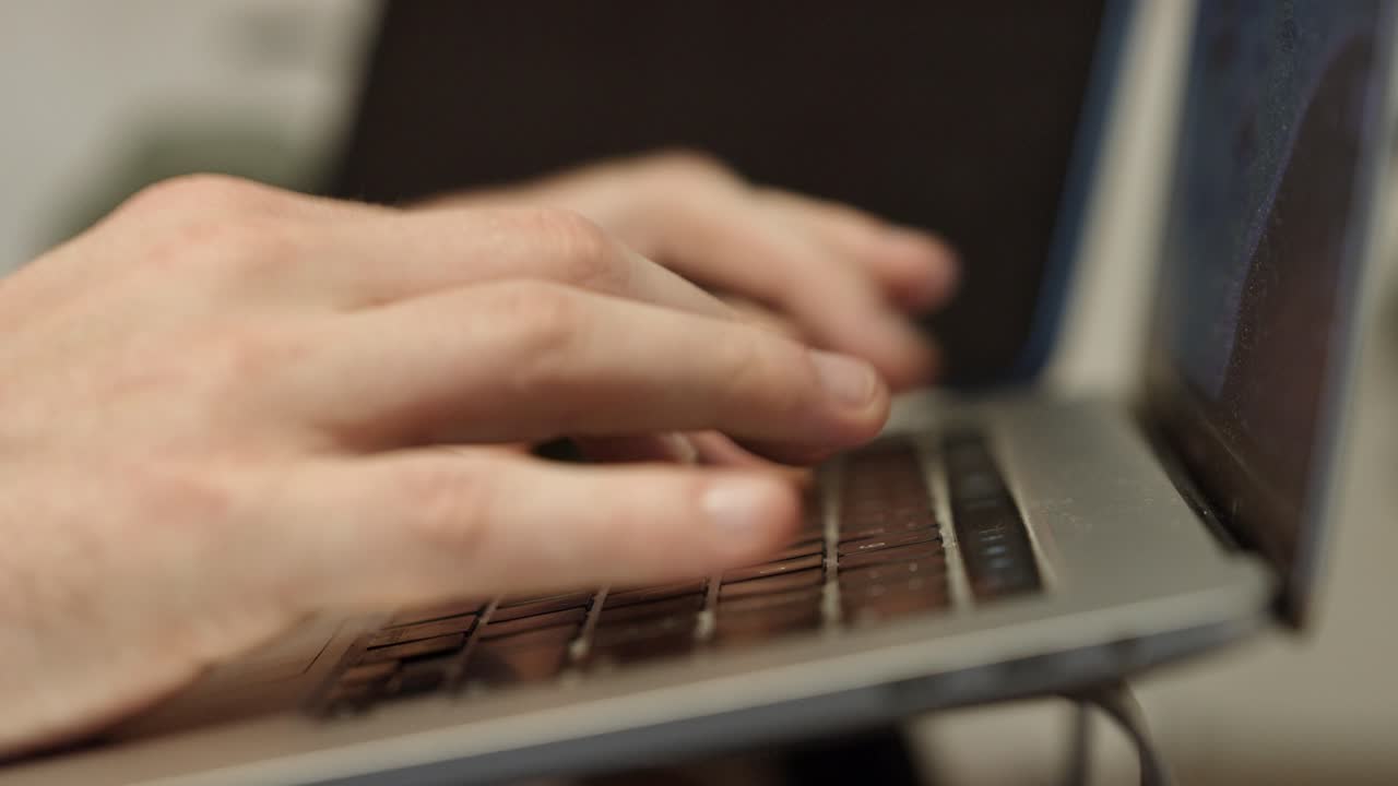 Dita che digitano su un laptop posizionato su un supporto. Scrivere da casa