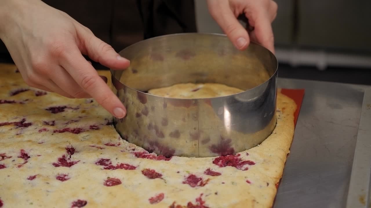 primer plano de un chef de pastelería cortando una forma redonda de una gran masa de galleta.