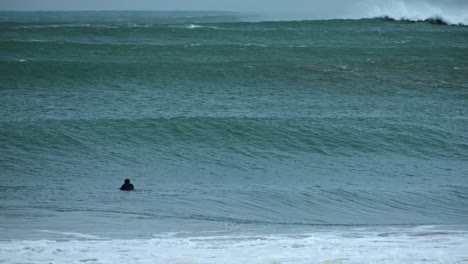 Zwei-Nicht-Erkennbare-Männerfiguren-Mit-Einer-Brandung-Vor-Großen-Wellen,-Die-An-Einem-Strand-Bremsen