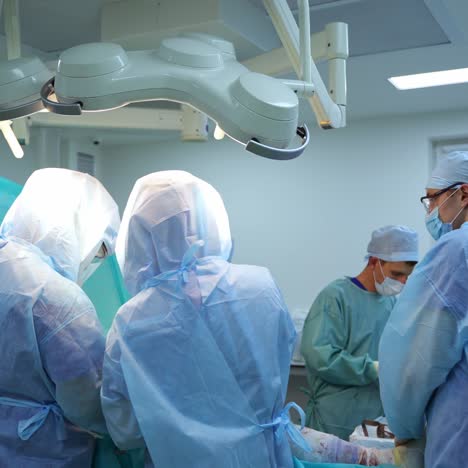 surgery in the operating theater. group of medical specialists in protective uniform conduct an operation to a patient in modern hospital.