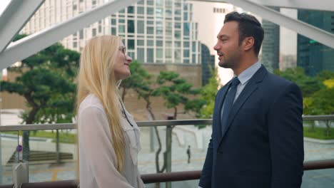 two business people meeting shaking hands talking chatting on street in downtown of modern city