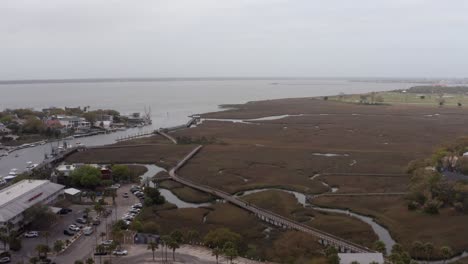 aerial rising dolly shot of the shem creek boardwalk along charleston harbor on a hazy day in mount pleasant, south carolina