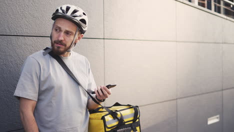 entregador de comida confuso com mochila térmica consulta um endereço em seu smartphone porque está perdido