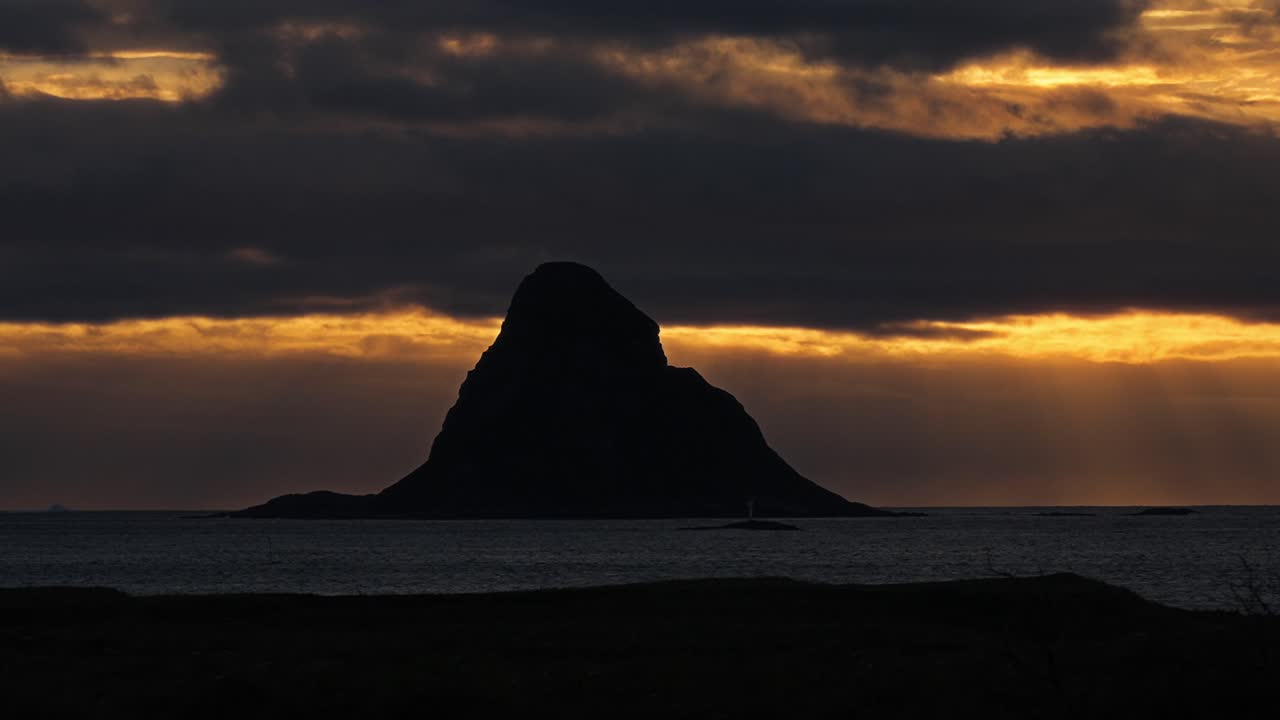 A dark silhouette of a mountain in the Vestarelen region during sunset
