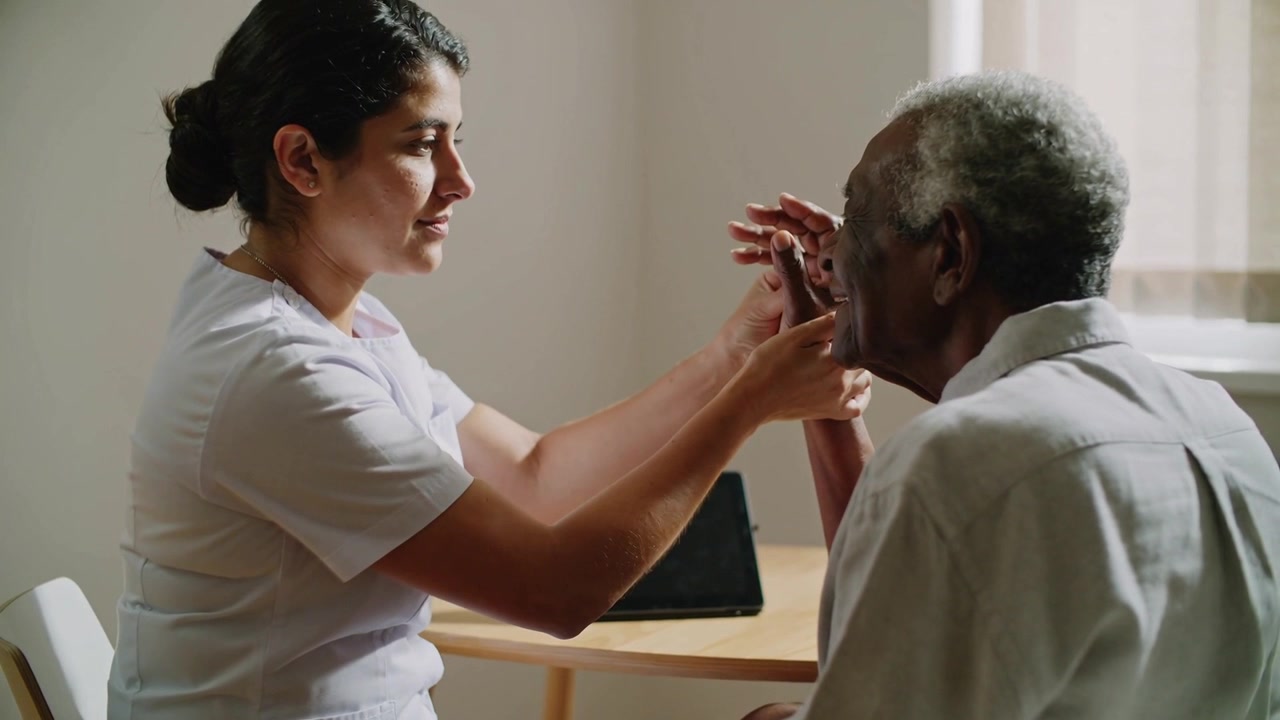 Taking patient's hand caregiver in scrubs guiding wrist and finger movement assessing motion