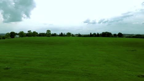 Flight-close-up-green-field-and-small-hill,-natural-landscape-near-village