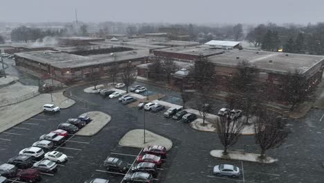 snowflakes falling on american high school and parking lot