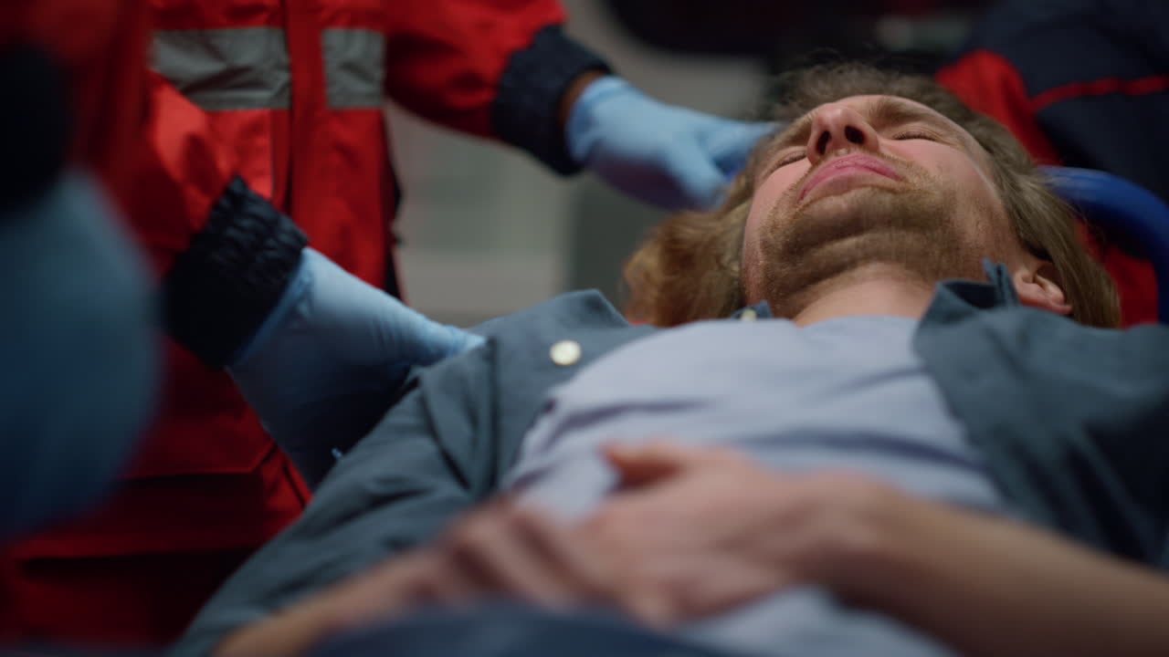 Rescue team of paramedics in gloves doing medical checkup to man