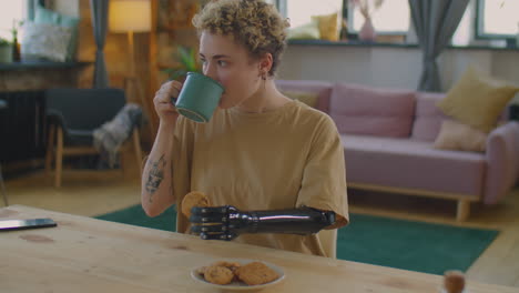 girl with prosthetic arm drinking tea with cookie at home