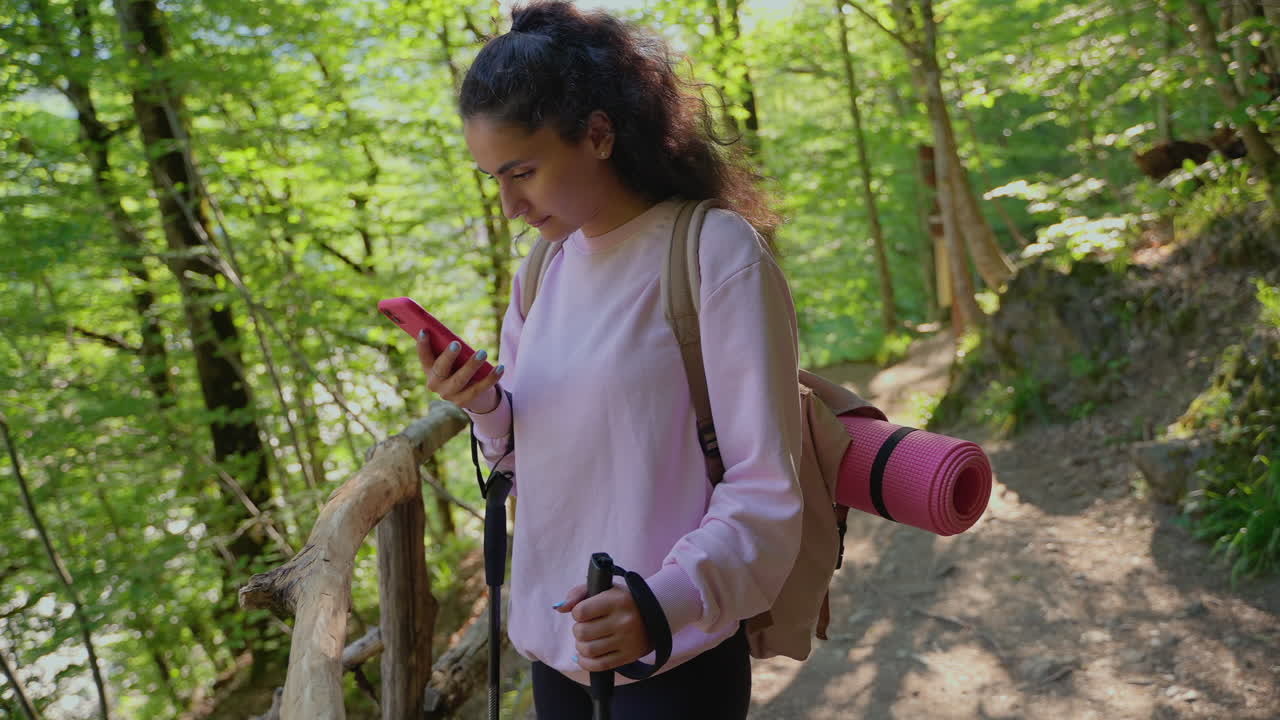 женщина, гуляющая в лесу с помощью телефона.