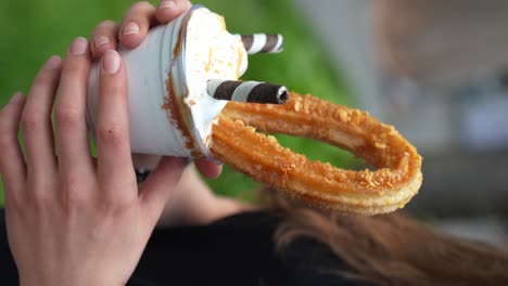 churro with an ice cream in hands of woman, close up, vertical shot