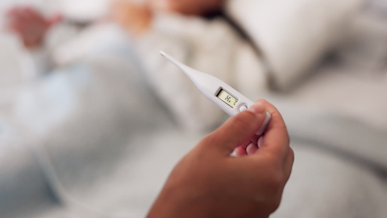 병든 아이의 부모, 손 및 온도계가 침대에 누워 있습니다.