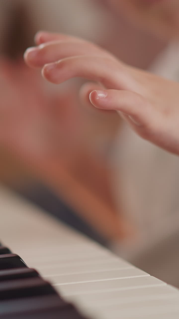 Toddler boy chubby fingers press piano keys learning simple composition on blurry background closeup. Little child plays classic music at home lesson