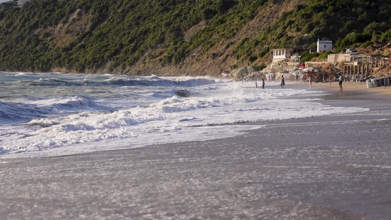 휴가 중인 관광객들과 함께 여름날 일몰 중에 아름다운 해변의 느린 움직임  ⁇