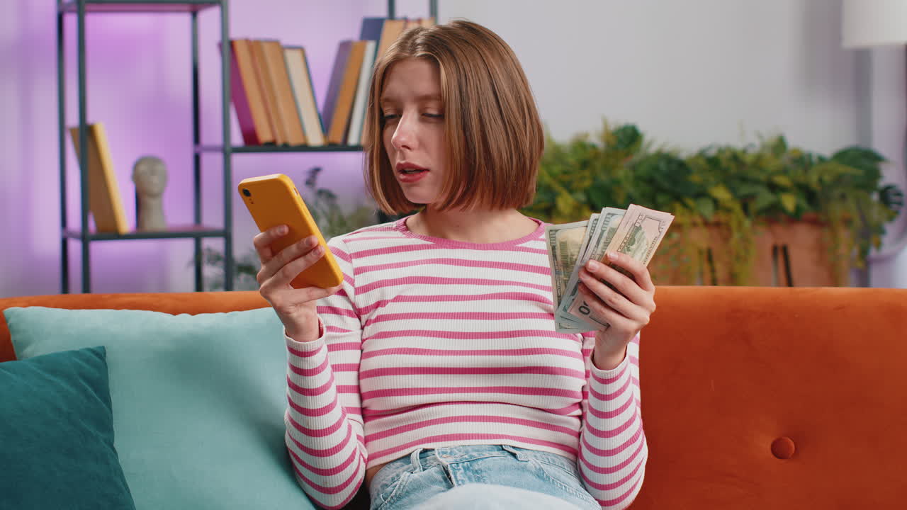 웃는 행복한 젊은 여성 현금 계산 스마트폰 사용 수입 절약 복권 승리 집에서 예산