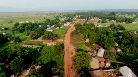 motorcycle traffic along a red dirt unpaved road in rural rukubi, nigeria - aerial flyover