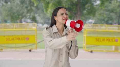 indian female police officer shouting on people using megaphone