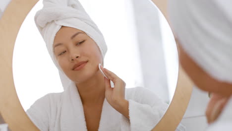woman cleansing her face in the bathroom