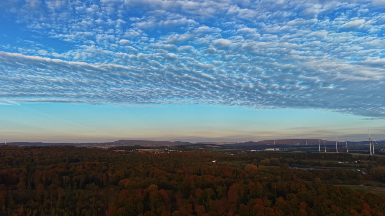 Vista panoramica di un vivace paesaggio autunnale al crepuscolo sotto un cielo materico, che mette in mostra la bellezza della natura nella campagna