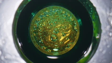 lager falling splashing flask closeup. golden alcohol drink overflowing top view