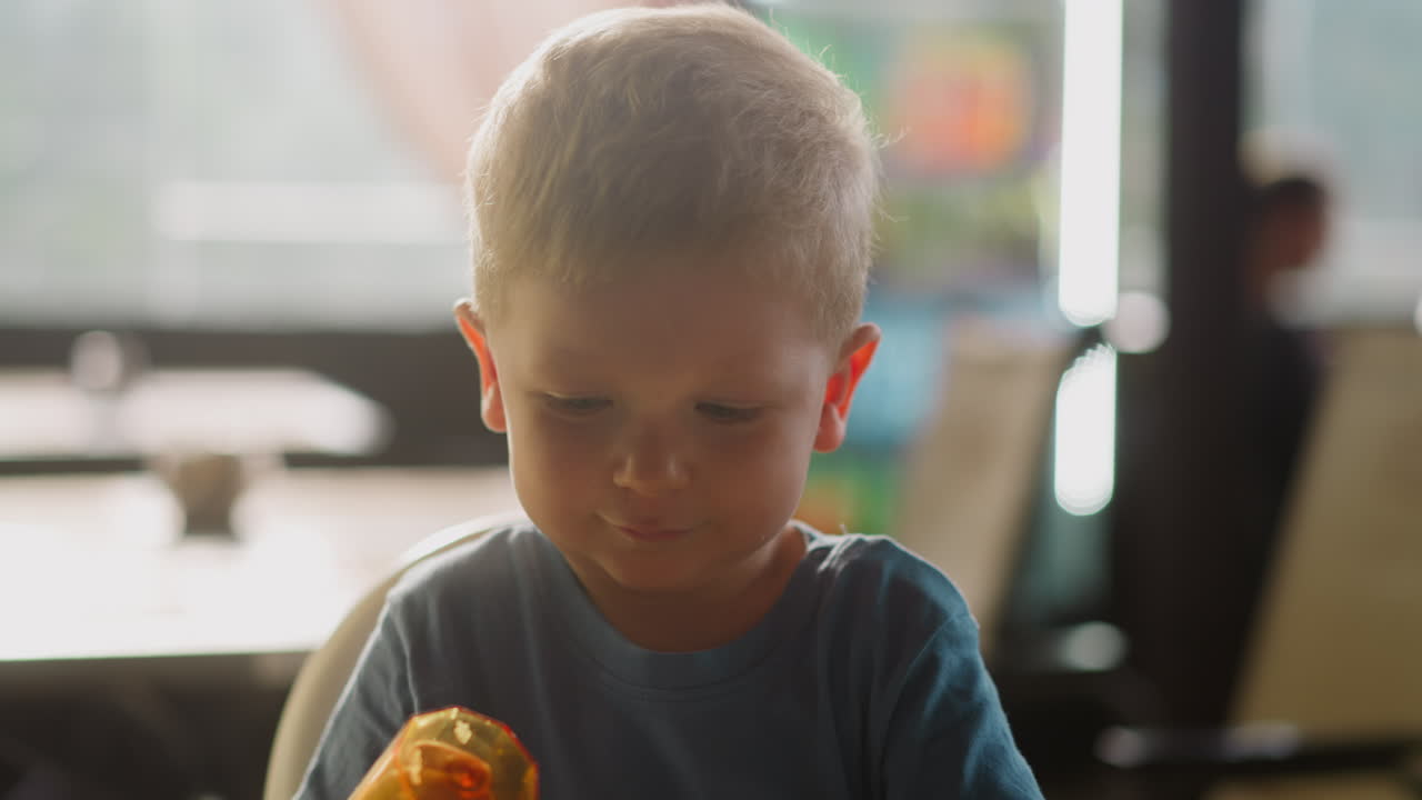 маленький мальчик ставит бокалы друг в друга за столом в кафе