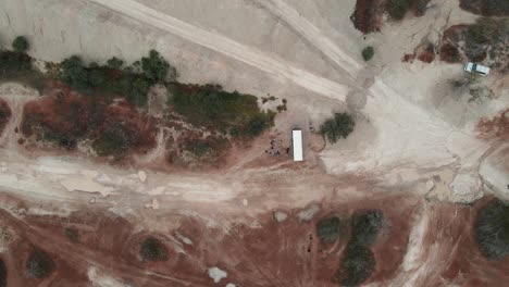 A-high-view-looking-down-at-a-tour-bus-with-people-surrounded-by-the-colourful-rich-soil-of-outback-Australia