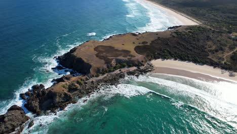 las olas rompiendo sobre la costa escarpada de mirame ahora promontorio en emerald beach, nueva gales del sur, australia