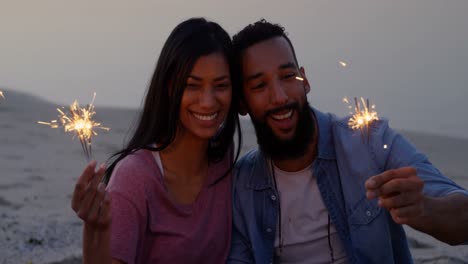 happy young mixed-race couple having fun with sparklers at beach 4k