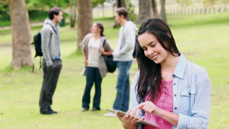 Frau,-Die-Ihren-Tablet-PC-Benutzt,-Bevor-Sie-In-Die-Kamera-Schaut,-Während-Sie-In-Einem-Park-Steht