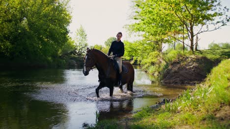 man horseback riding through river in countryside