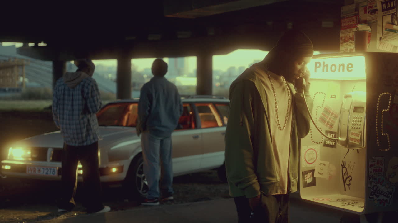 hombre afroamericano marcando y hablando emocionalmente en el teléfono de la calle por la noche