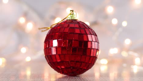 christmas red disco ball ornament with blinking lights behind