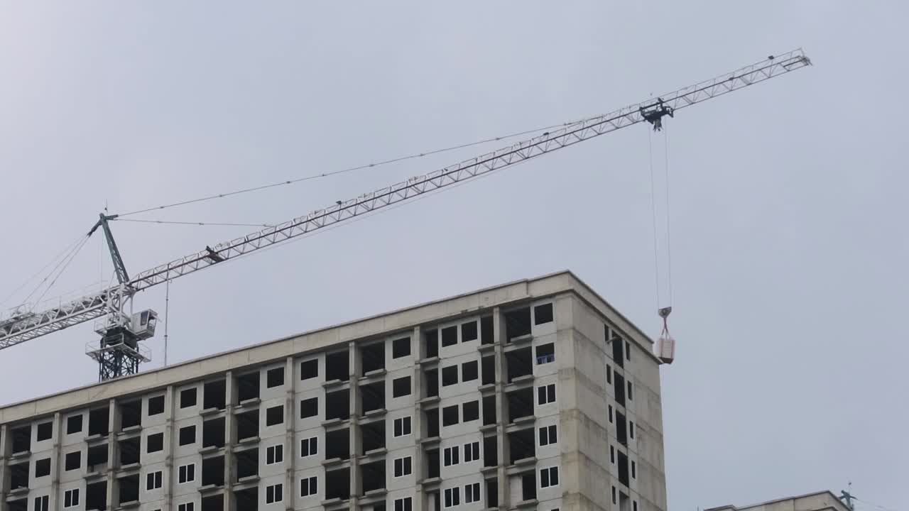 Una grúa alta trabajando en la construcción de un rascacielos, con un ascensor moderno descendiendo.
