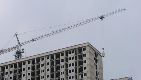 Grúa-Alta-Trabajando-En-Un-Ascensor-Moderno-Bajando-En-Un-Edificio-De-Construcción-De-Rascacielos