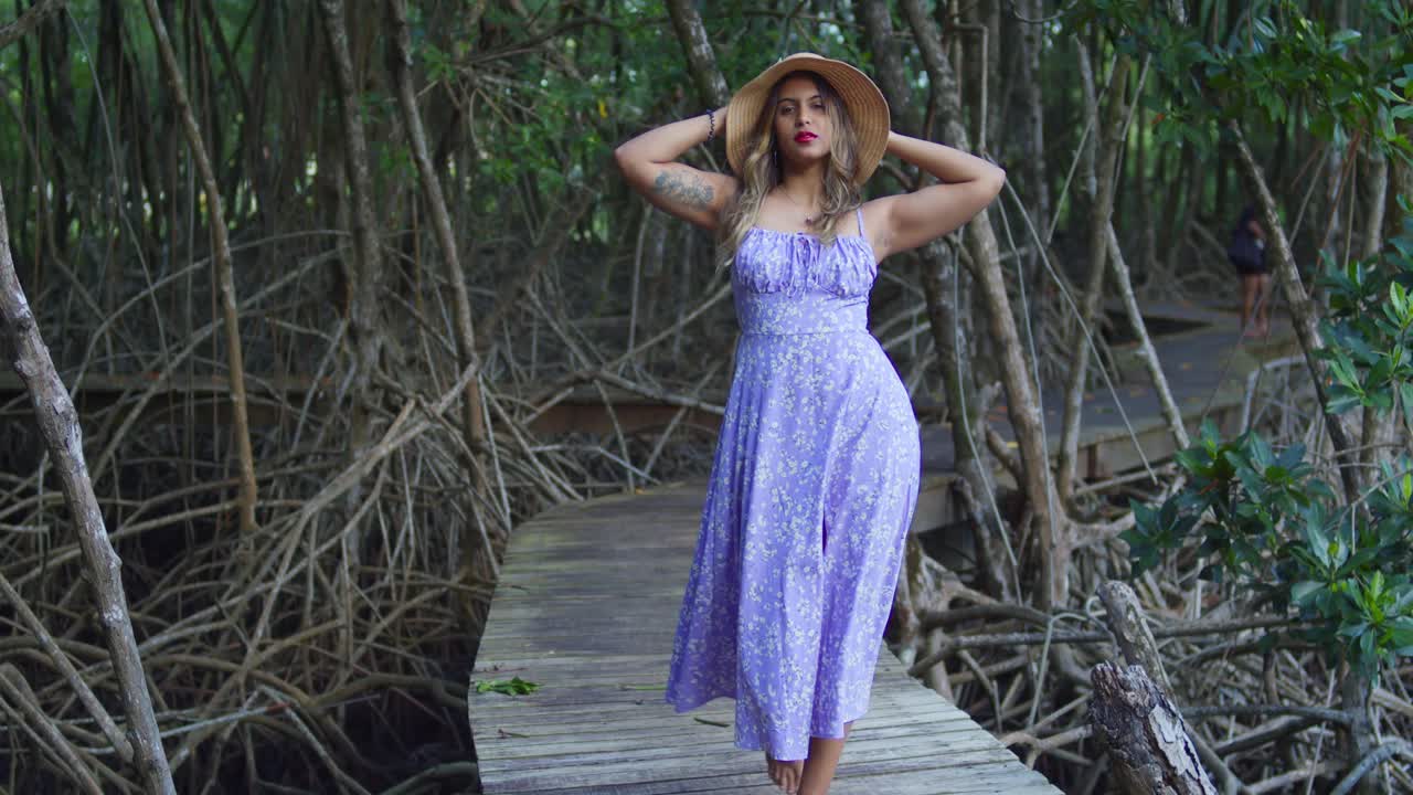 Jovem mulher indiana num vestido de verão floral azul claro, numa passarela de madeira na floresta; rodeada por árvores antigas e um murmúrio suave.