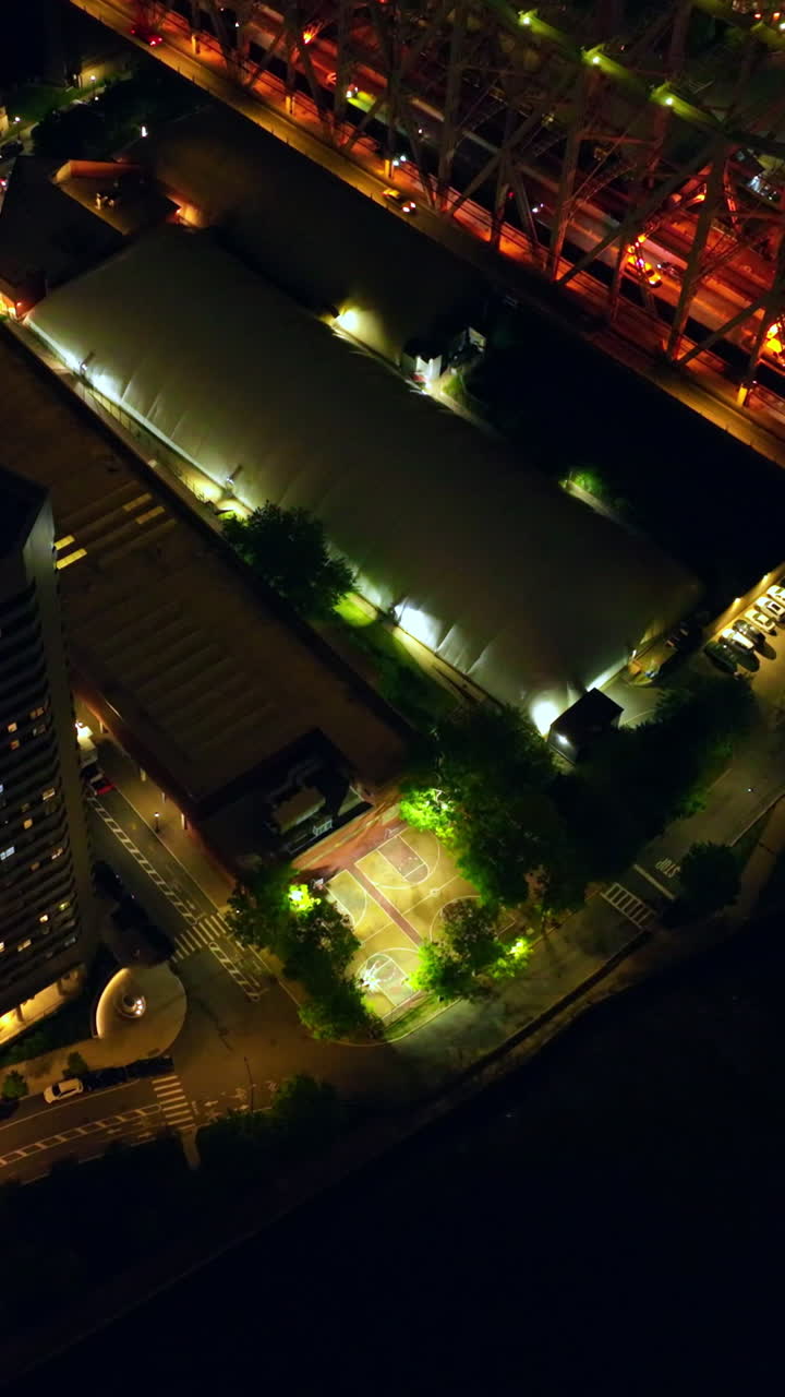 Beautifully lit island and bridge crossing it. Numerous cars riding by the bridge at night. Magic New York from top. Vertical video