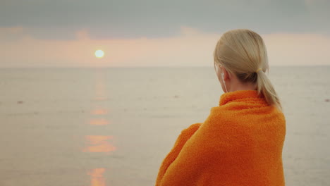 Conoce-El-Amanecer-En-El-Mar-Solo,-Una-Mujer-Envuelta-En-Una-Manta-Parece-Que-Sale-El-Sol-Sobre-El-Mar